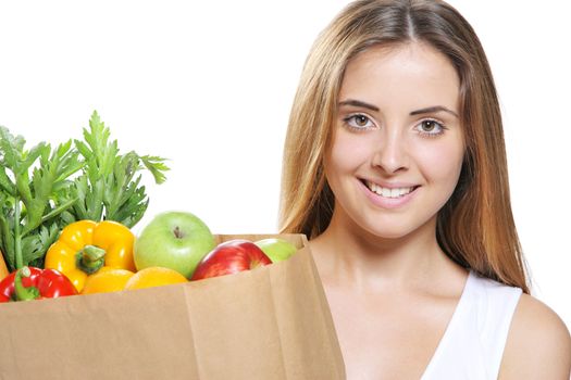 Portrait of smiling young woman holding a shopping bag full of groceries on white background