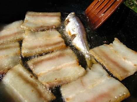 The image of tasty fried bacon on a frying pan