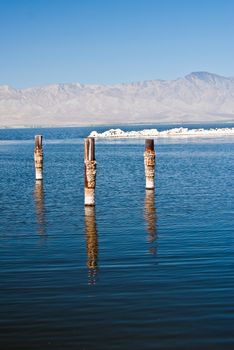 Posts reflect in water on a hazy summer day at Salton Sea California