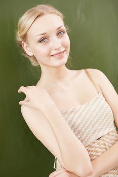 Young female teacher standing near blackboard at school