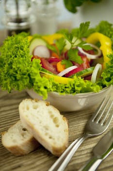 fresh tasty healthy mixed salad and bread on wooden table