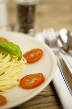 fresh tasty pasta with tomato and basil on wooden table