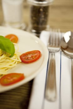 fresh tasty pasta with tomato and basil on wooden table