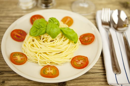 fresh tasty pasta with tomato and basil on wooden table