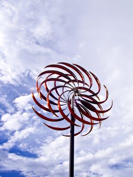Wind moves the blades of  red metal art