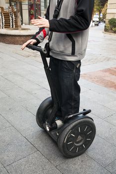 A man denstrates how to ride a Segway in the street.