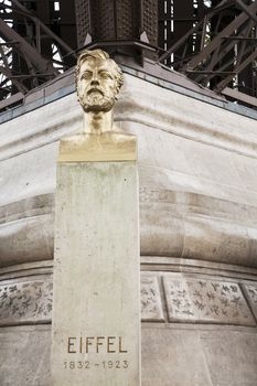 Bust of Gustave Eiffel the creator of the famous Eiffel Tower in Paris, France in front of the tower itself.