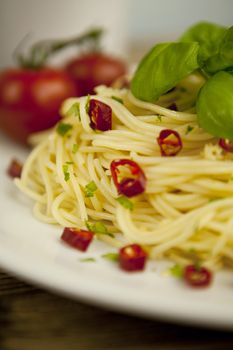 fresh pasta with basil and red chilli on wooden table