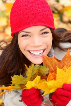 Autumn girl in fall colors smiling happy. Fall woman portrait of cheerful and beautiful mixed race Asian Caucasian young woman.