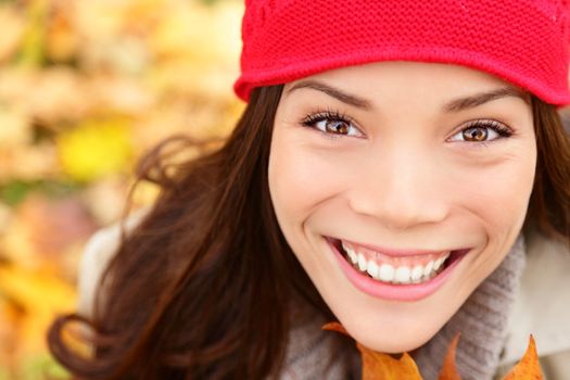 Autumn girl in fall colors smiling happy in closeup portrait. Fall woman cheerful and beautiful. Multiethnic Asian Caucasian young woman.