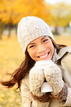 Autumn lifestyle woman drinking coffee. utumn portrait of happy lovely and beautiful mixed race Asian Caucasian young woman in forest in fall colors.