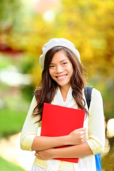 Young woman student in autumn park. Young woman student in autumn park. Asian woman smiling happy on spring day outside in park . Pretty mixed race Caucasian / Chinese Asian young woman.