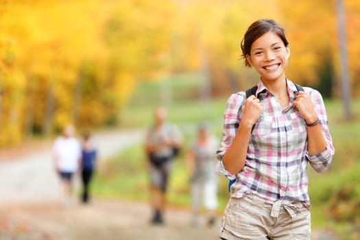 Autumn hiking girl. Female hiker looking around in forest in autumn colors. Beautiful young woman on hike.