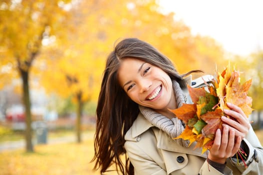 Autumn girl playing in city park. Fall woman portrait of happy lovely and beautiful mixed race Asian Caucasian young woman in forest in fall colors.