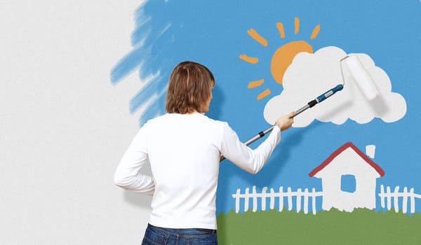 Young man with a paintbrush and family picture on the wall