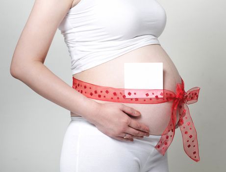 Bow and Note on Pregnant Belly over grey background