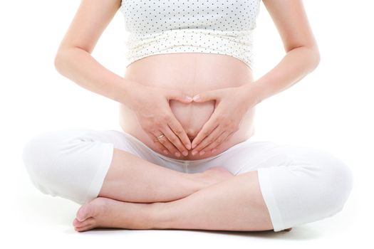 Pregnant woman forming love shape on her 8 months pregnant belly