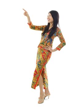 Full body Asian female with batik dress pointing on empty space, over white background