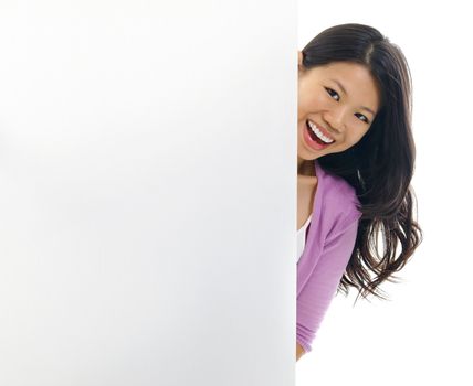 Cheerful young Asian woman hiding on a blank space.