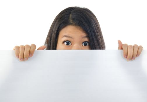 Shock Asian woman open eyes big, hiding behind a white card and covering mouth.