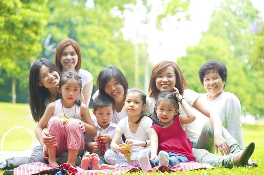 Happy Asian family enjoying picnic at outdoor park