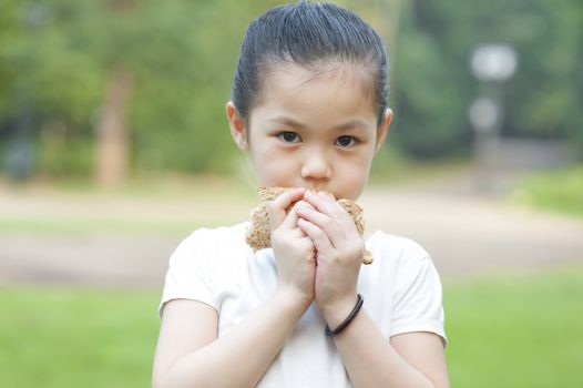 Little Asian girl eats a sandwich on fresh air