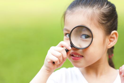 Little girl exploring nature by magnifier