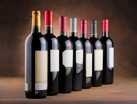 Red wine bottles in a row with empty labels on a mottled canvas background
