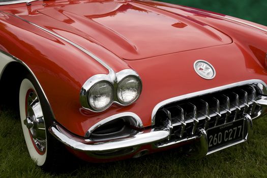 the hood of a classic red chevrolet corvette with front grill and badge