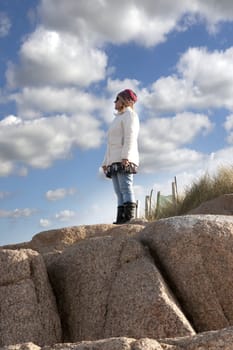 woman looking out to sea at the top of old natural rock formation on a beach in county Donegal, Ireland