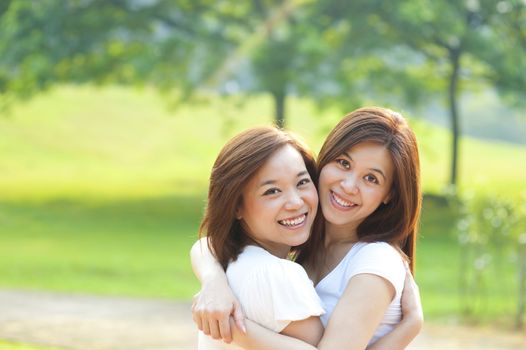 Two cheerful Asian girls having fun at outdoor park