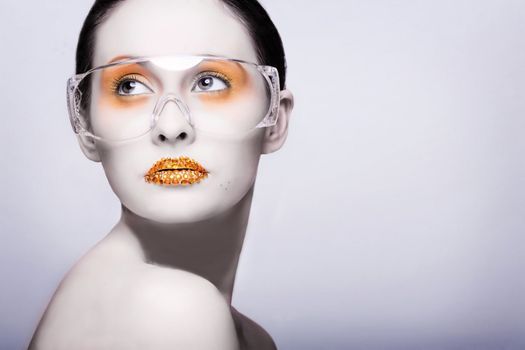 Young caucasian woman with gold fashion makeup wearing clear glasses and gold diamonties on her lips