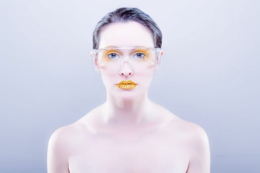 Young caucasian woman with gold fashion makeup wearing clear glasses and gold diamonties on her lips