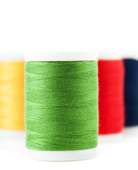 Four thread spools over white background