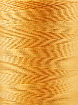 Macro view of yellow thread wound on a spool