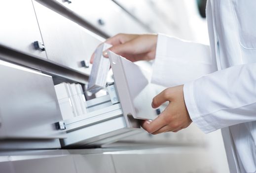 Close up view of pharmacist taking medicine from drawer