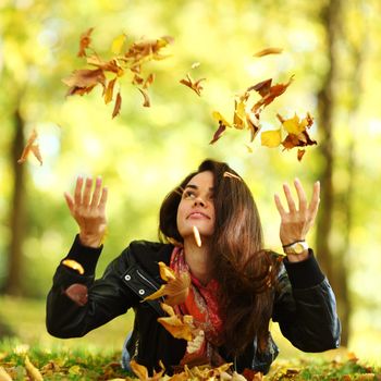 woman drop up leaves in autumn park