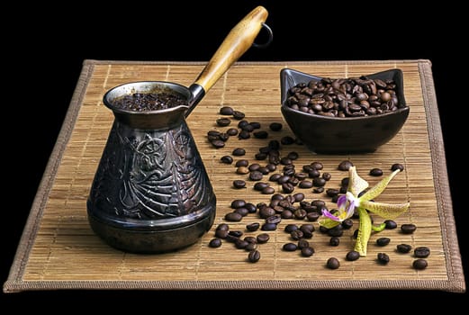 Coffee turk with coffee beans and orchid on black background isolated.