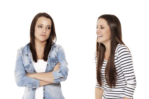 teenager laughing at her upset sister on white background