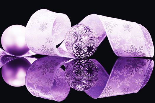 purple christmas balls and beautiful ribbon on a black mirror