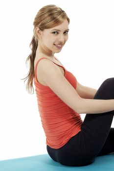 fitness woman sitting on a blue mat making a break on white background