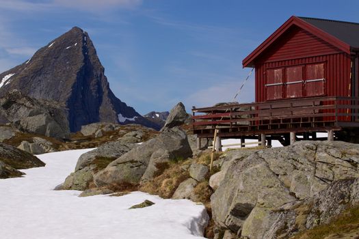 Mountain cabin on Lofoten islands in Norway with sharp mountain peak towering above