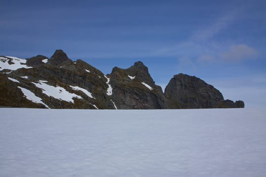 Snow fields in the arctic Norway on Lofoten islands during summer with sharp mountain peaks towering above them