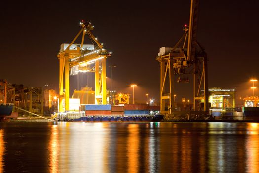Container Cargo ship with working crane in shipyard at dusk unloading goods for Logistic Import Export background