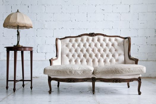 White genuine leather classical style sofa in vintage room with desk lamp