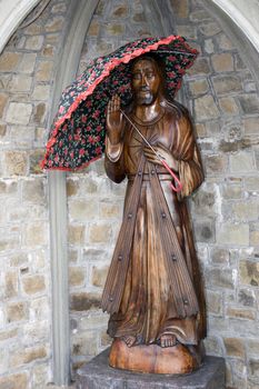 a wooden carved statue of Jesus holding an umbrella in Ireland
