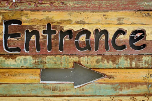 Text "Entrance" and arrow engraved on the wood sign