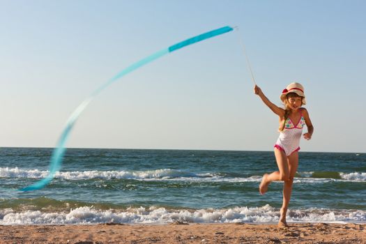 girl with gymnastics ribbon on the sea beach