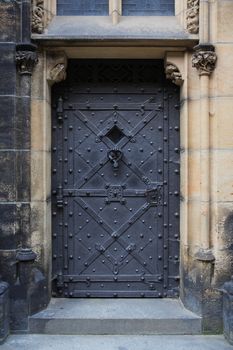 Ancient building with gloomy black metal door