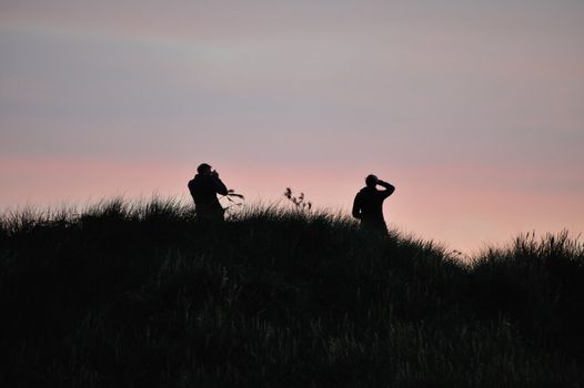 The silhouette of a photographer and his model in the sunset.
